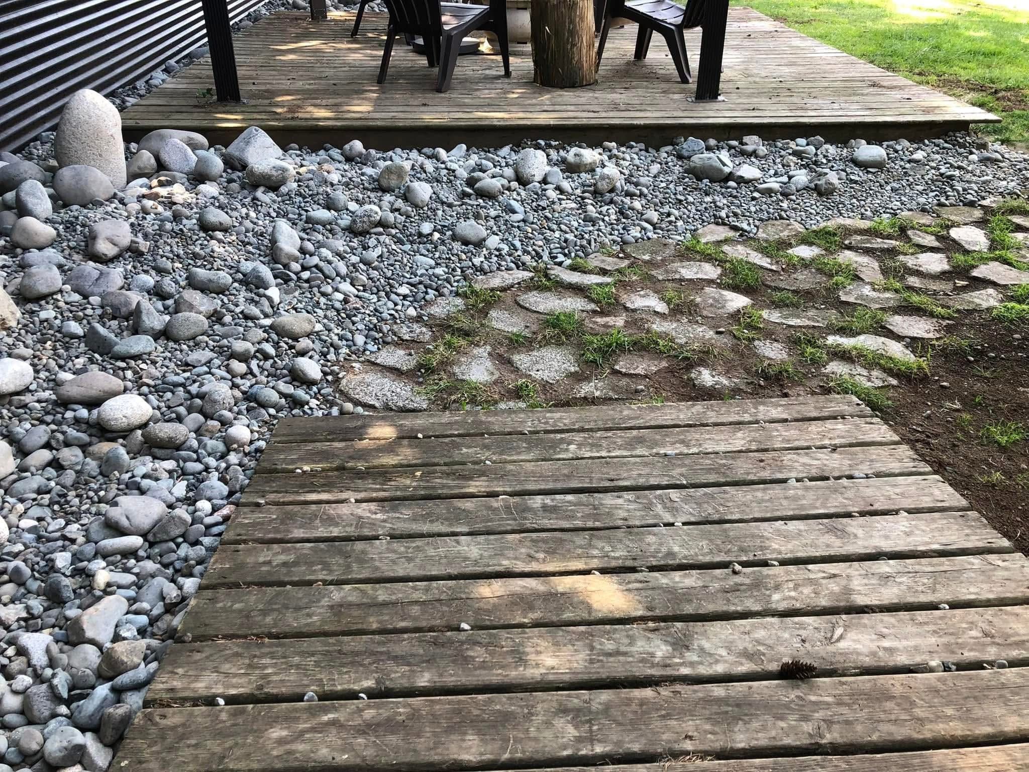 River-rock dry creek beside a wood deck and patio