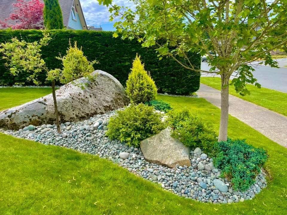 Polished boulder rock garden with topiary spheres, junipers, and tumbled river stones