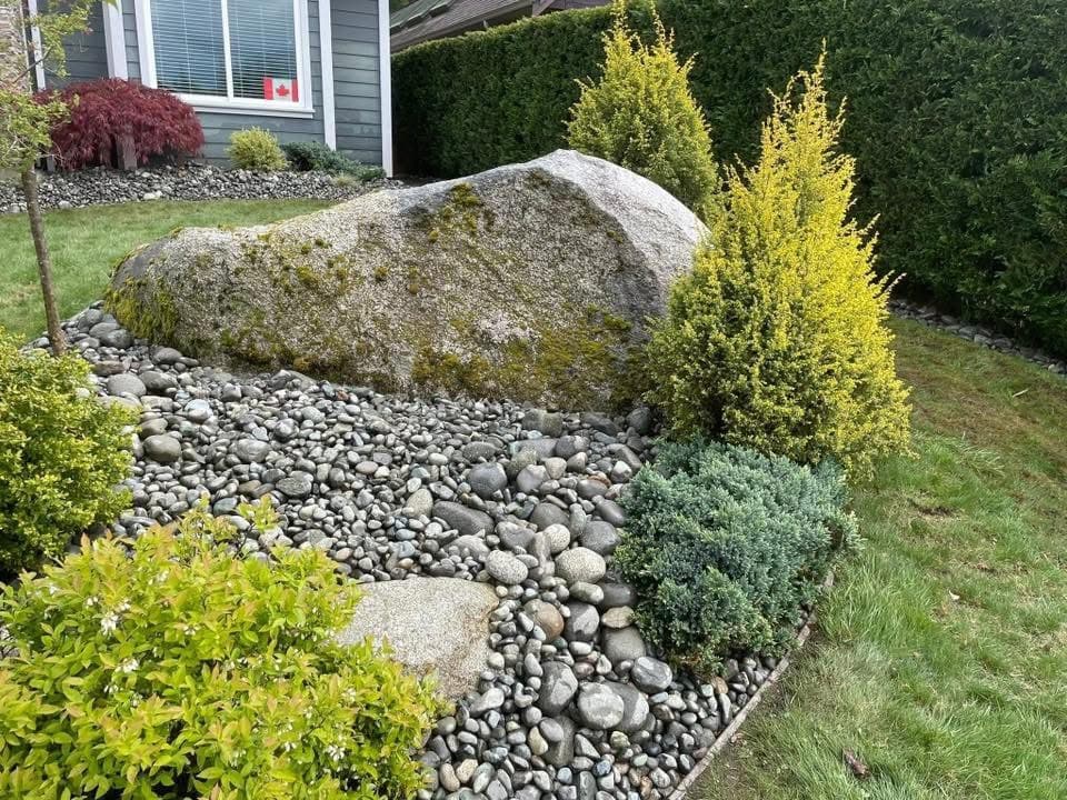 Large mossy granite boulder accented by river stones and sculpted juniper