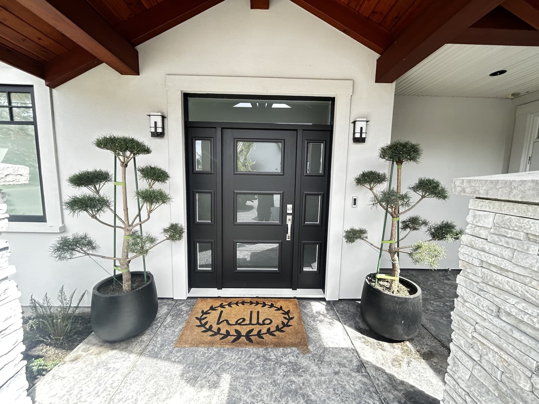 Symmetric front-door composition with twin sculpted topiaries flanking a black double door