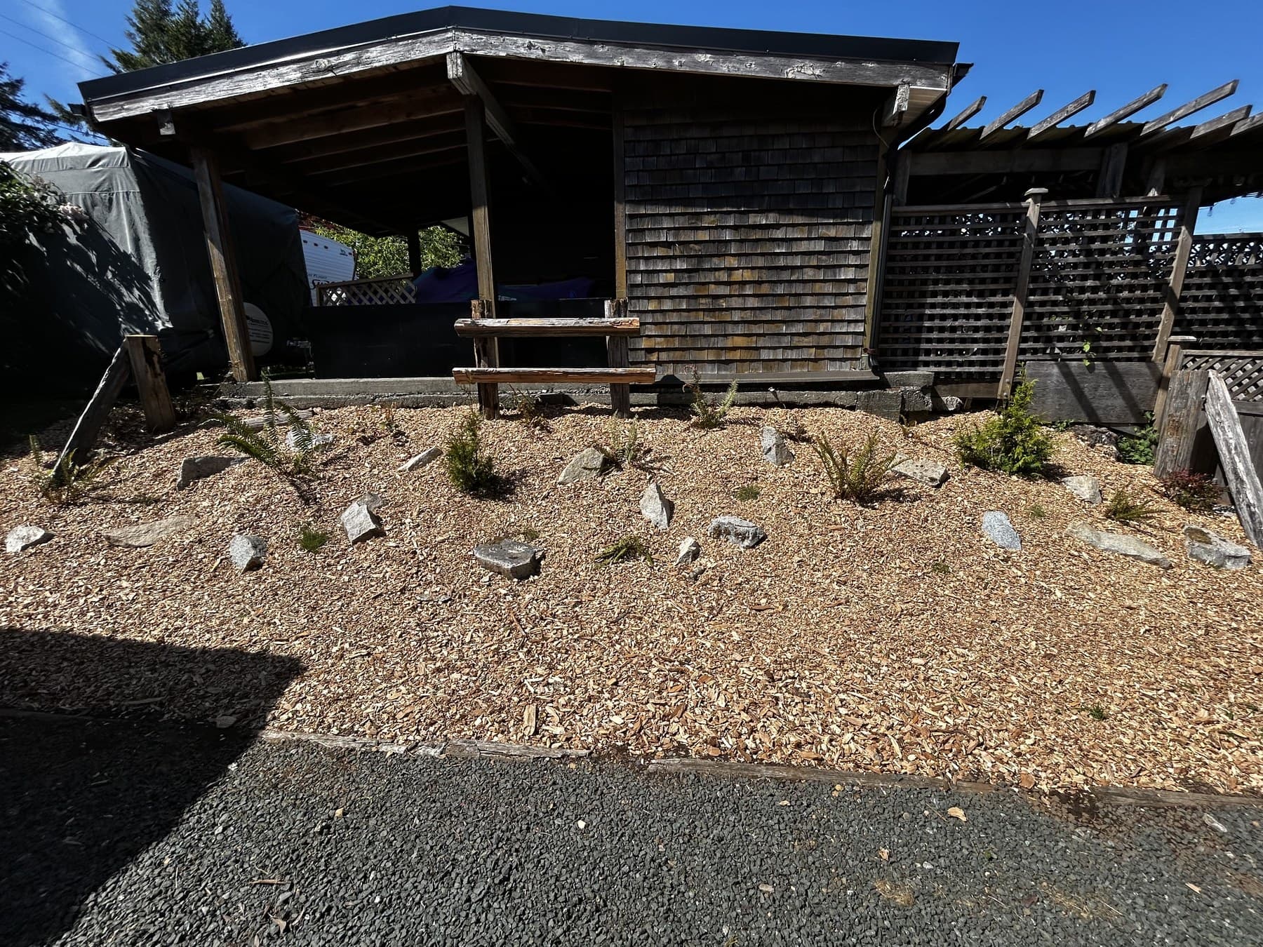 Wood structure with bark-mulch bed and stone accents in a front yard